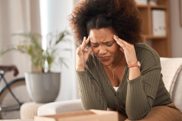 An adult Black woman stressed out, rubbing her temples