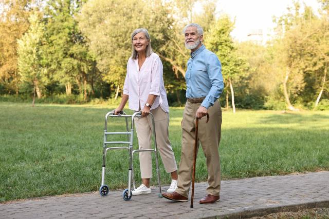 An older woman using a walker and an older man using a cane