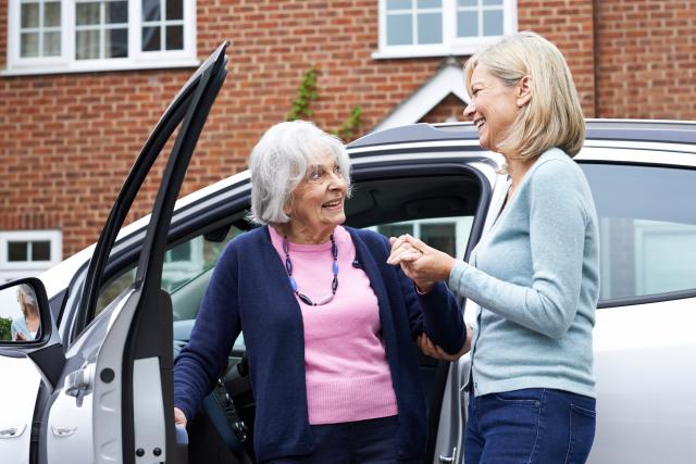 An older woman greeting another as she exits a car