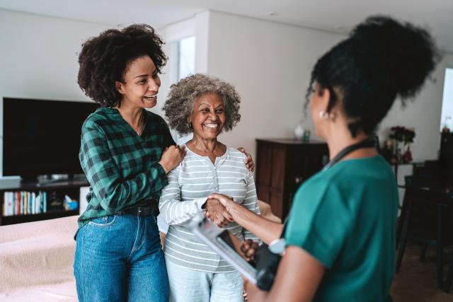 A woman with her older adult mother talking to a home nurse